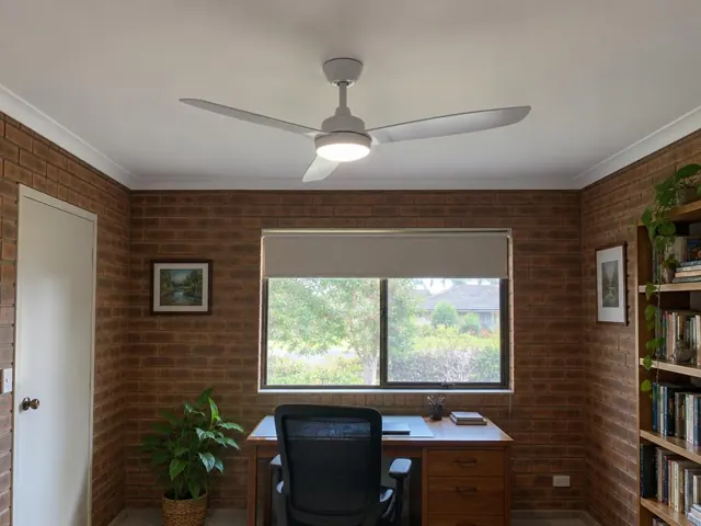 Ceiling fan in a brick-walled home office with window, desk and shelves in Jewells