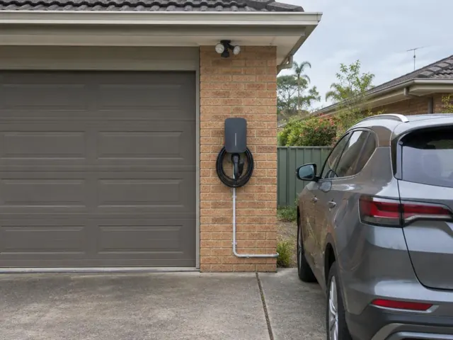 Wall-mounted EV charger on a brick garage wall beside a driveway in Floraville