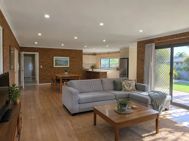 Open-plan living room with recessed ceiling downlights, brick walls and sliding doors in Floraville